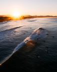 Belongil Beach, Byron Bay wave breaking with surfers sitting and paddling along the lineup in low sunset light