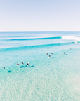 Surfers in a shallow surf lineup at Second Bay, Coolum with clean wave lines forming across clear water over sand