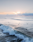 Surfers at Suffolk Park Beach, Byron Bay riding gentle waves in soft morning light along the Australian east coast.