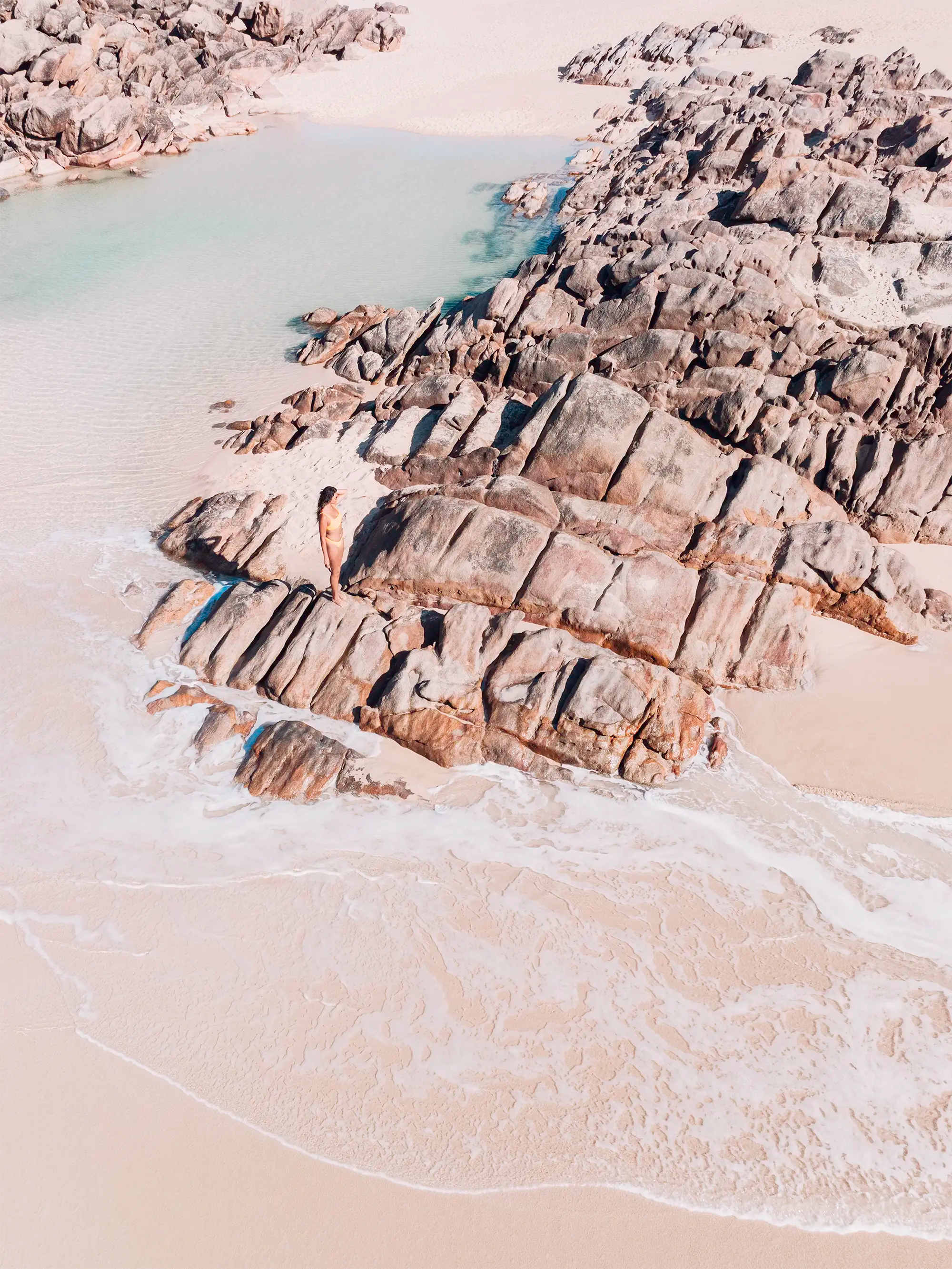 Aerial view of Injidup Beach, Yallingup with granite rocks surrounding a tidal pool with shallow clear water and coastal edges.