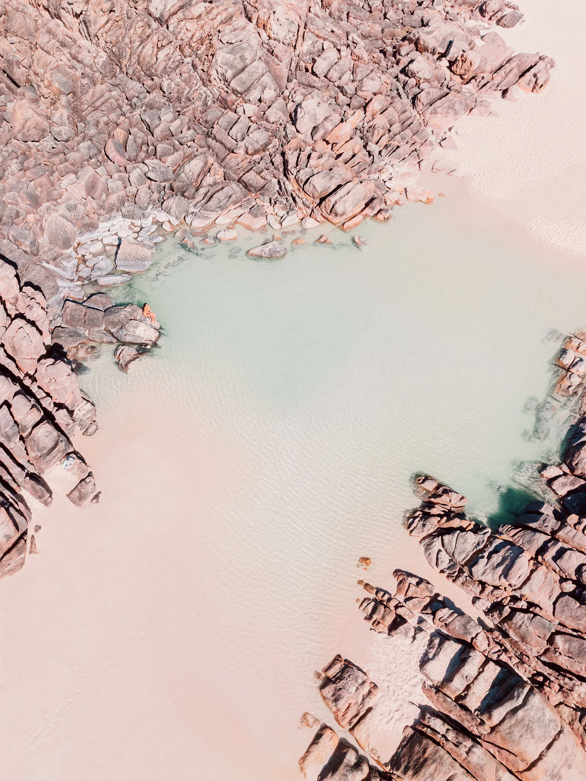 Aerial view of Injidup Beach, Yallingup with a rock-lined tidal pool bordered by granite formations and pale sand with shallow clear water