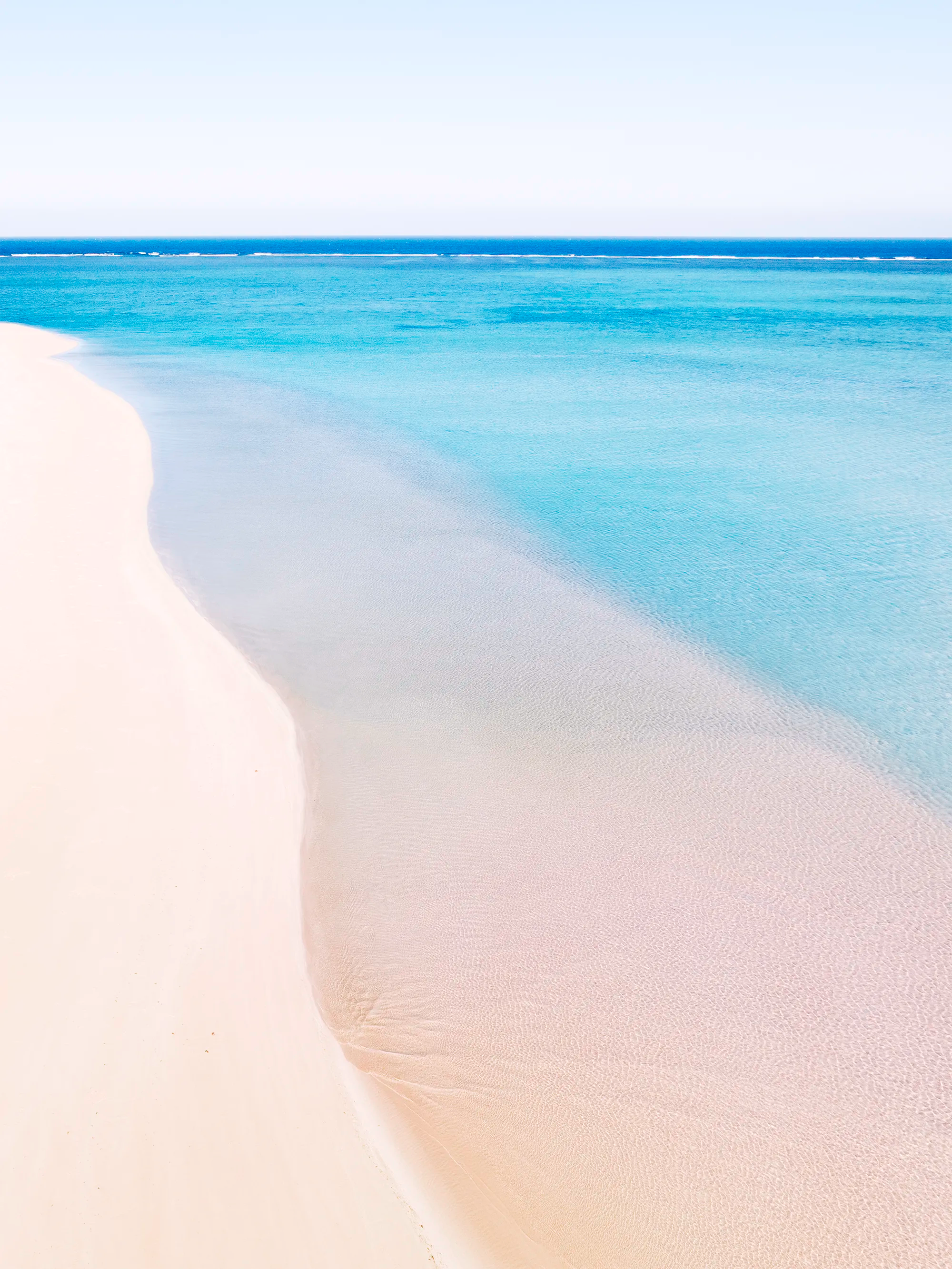 Sandy Bay, Cape Range showing pale sand shoreline meeting shallow clear water with a soft curved edge and minimal surface texture